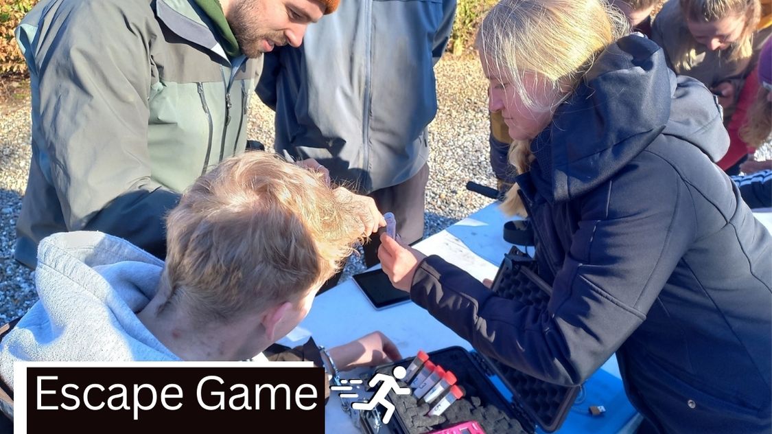 Billedet viser en gruppe mennesker, der er dybt koncentrerede om et "Escape Game" under et teambuilding-event i Aarhus. De er samlet omkring et bord med forskellige gåder og genstande, som de skal bruge til at løse spillets udfordringer. Denne aktivitet er ideel for teambuilding, da den kræver samarbejde, kreativ tænkning og kommunikation mellem deltagerne for at løse mysterierne og "undslippe" indenfor tidsgrænsen.